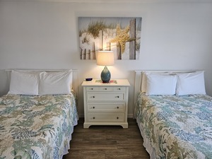 Room 29 bedroom, 2 double bds, beach-themed picture on wall